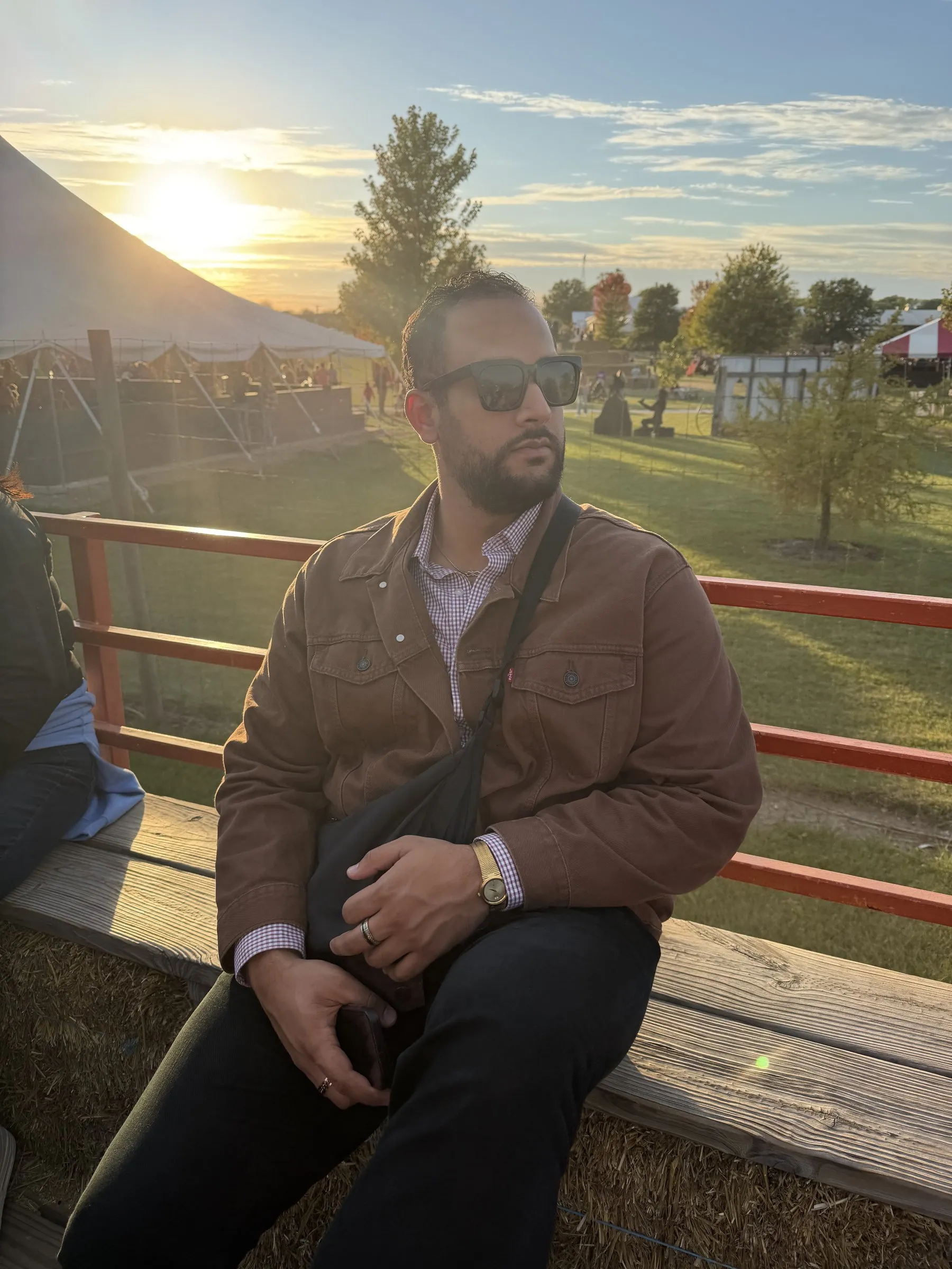 Addy at an autumn fair at golden hour, sitting on a hay wagon and looking out across the field